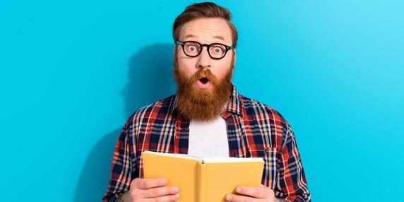 Mann liest ein Buch und schaut freudig überrascht